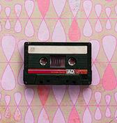 black cassette tape on top of a pink retro pattern